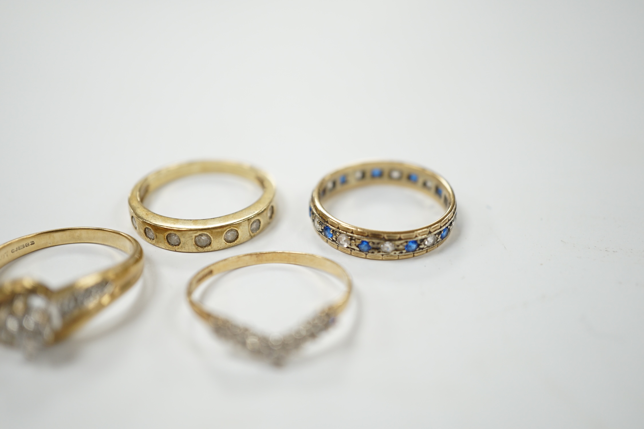 Two modern 9ct gold and diamond set rings and a 9ct gold, simulated diamond set chevron shaped ring and one other 9ct and paste set band, gross weight 9 grams. Condition - poor to fair